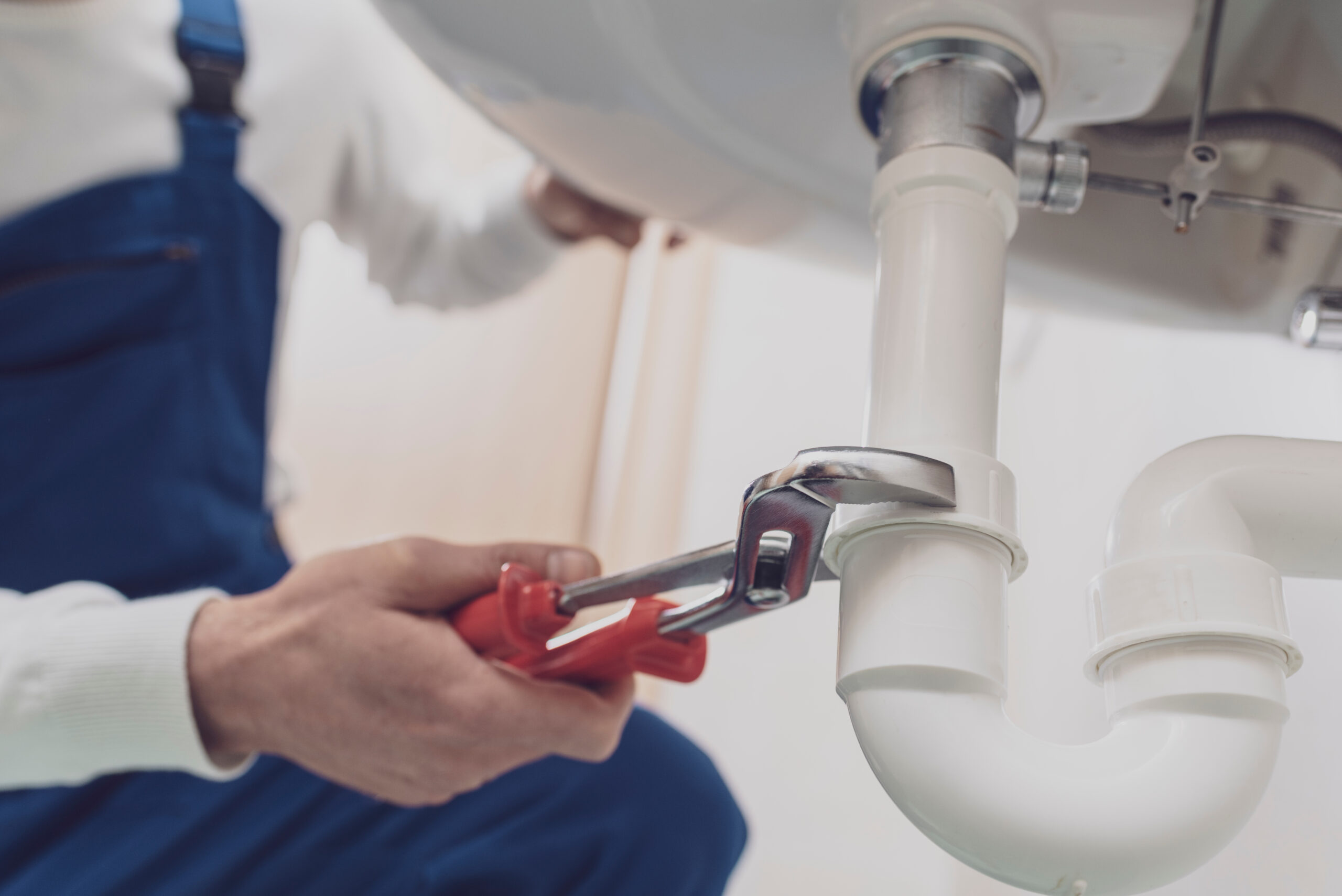Professional plumber installing or fixing a sink at home